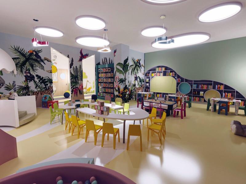Kleurrijke kinderspeelruimte met kleine stoelen, tafels en boekenplanken in een lichte kamer.