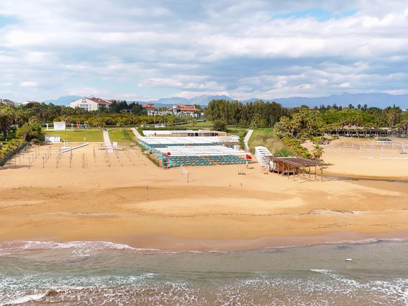 Breed zandstrand met accommodatie en groene gebieden op de achtergrond