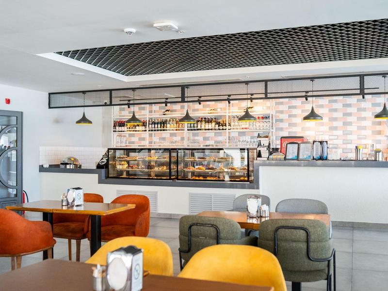 Modern café met kleurrijke stoelen en een toonbank met gebak in een lichte omgeving