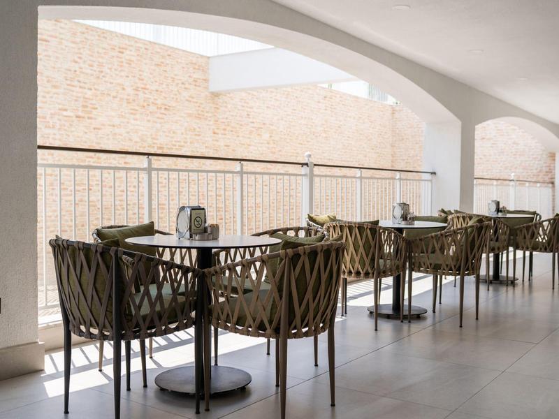 Moderne buitenruimte met elegante tafels en stoelen onder grote boogramen.