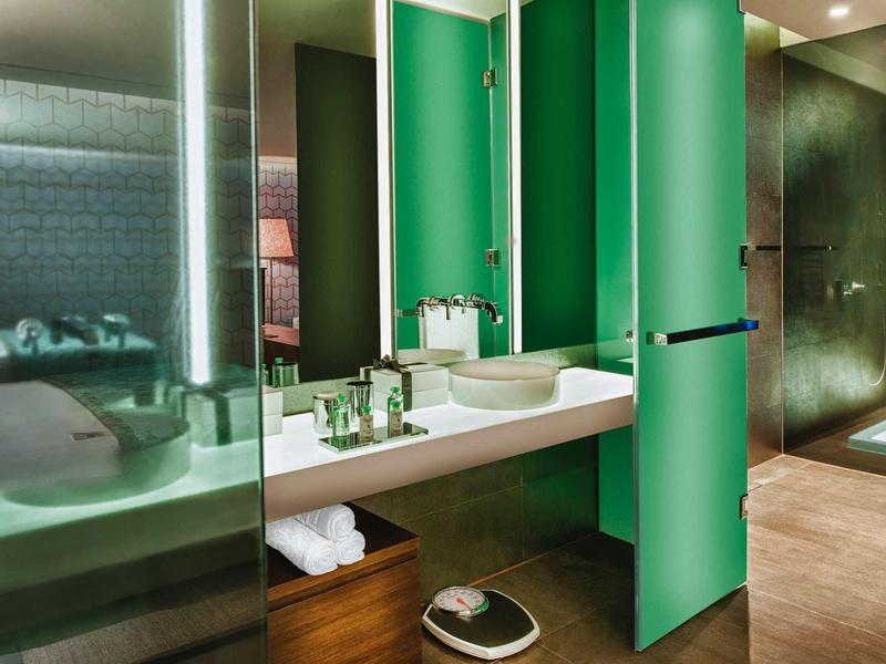 Moderní koupelna se umyvadlem, zrcadlem, zelenými dveřmi a odděleným sprchovým koutem.