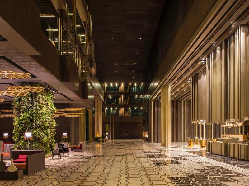 Moderní hotelová hala s luxusní výzdobou a teplým osvětlením.