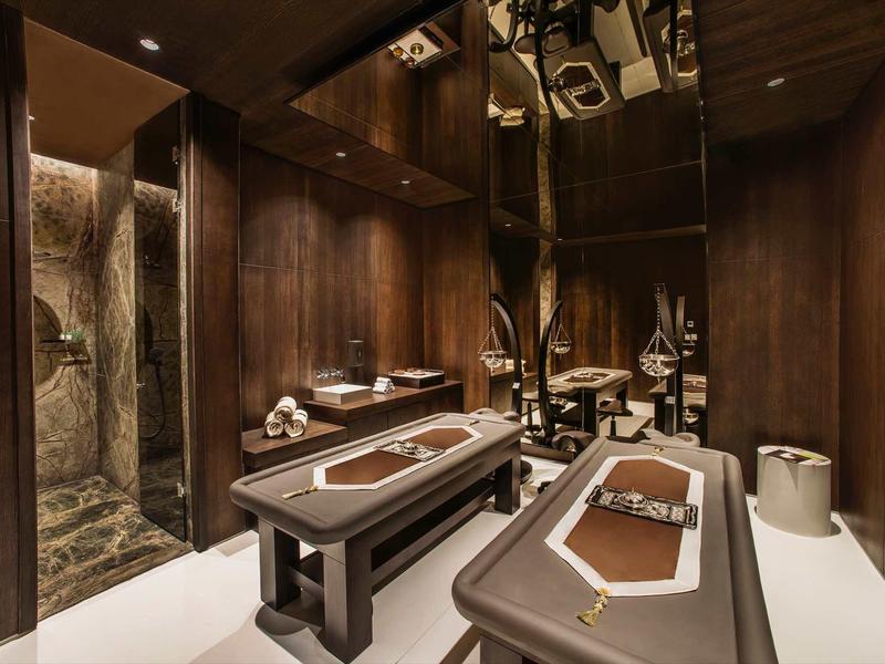 Elegantní masážní místnost s dřevěnými stoly a tlumeným osvětlením.