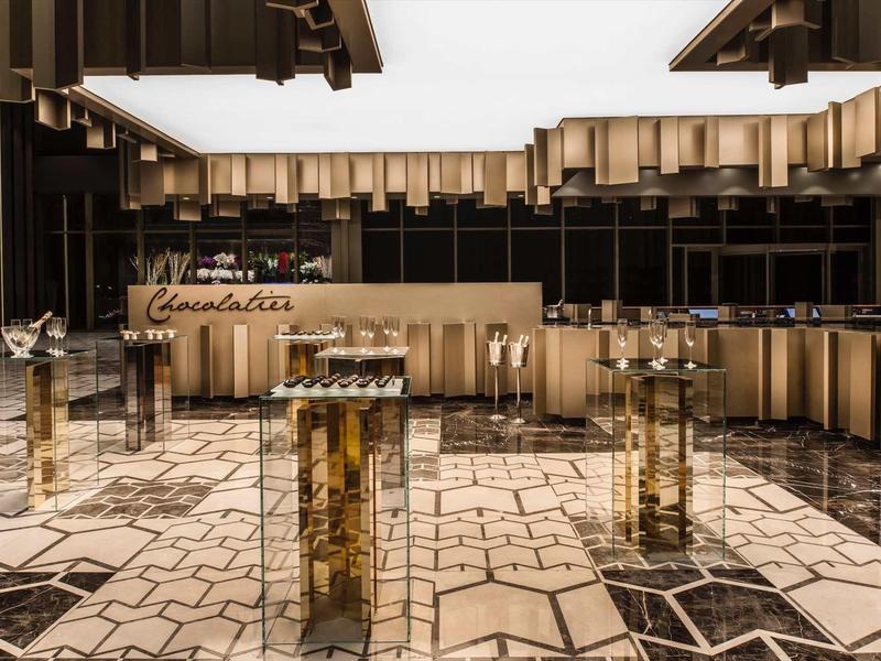 Moderní interiér hotelové haly s osvětlenou recepcí a geometrickou podlahou.