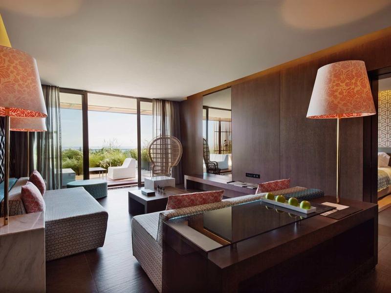 Moderní hotelový salón s elegantním nábytkem a výhledem na zelenou terasu.