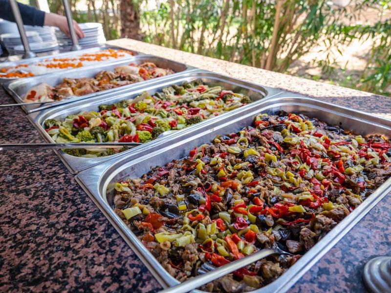 Několik táců s různými saláty a antipasti na venkovním bufetu.