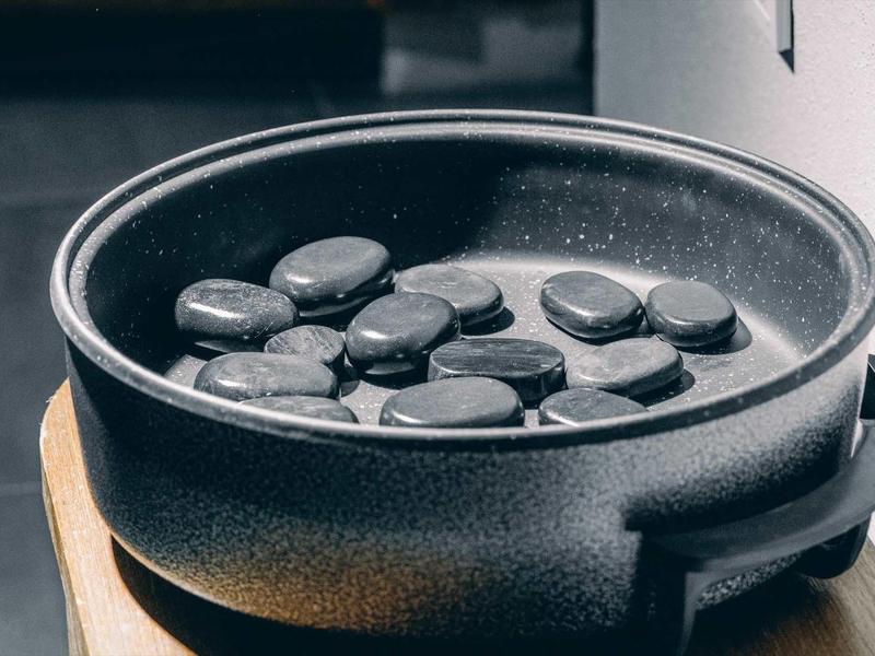 Černé kameny leží v černé misce s vodou na dřevěném podnosu.