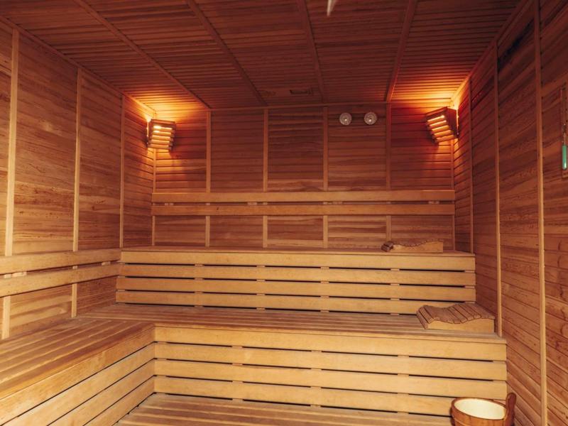 Saunová místnost s dřevěnými stěnami, lavicemi a tlumeným osvětlením.
