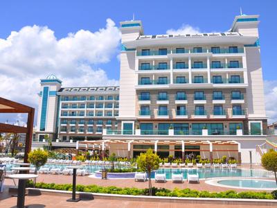 Modernes mehrstöckiges Hotel mit blauer Fassadendekoration, großem Pool und Sonnenterrasse bei Sonnenschein.