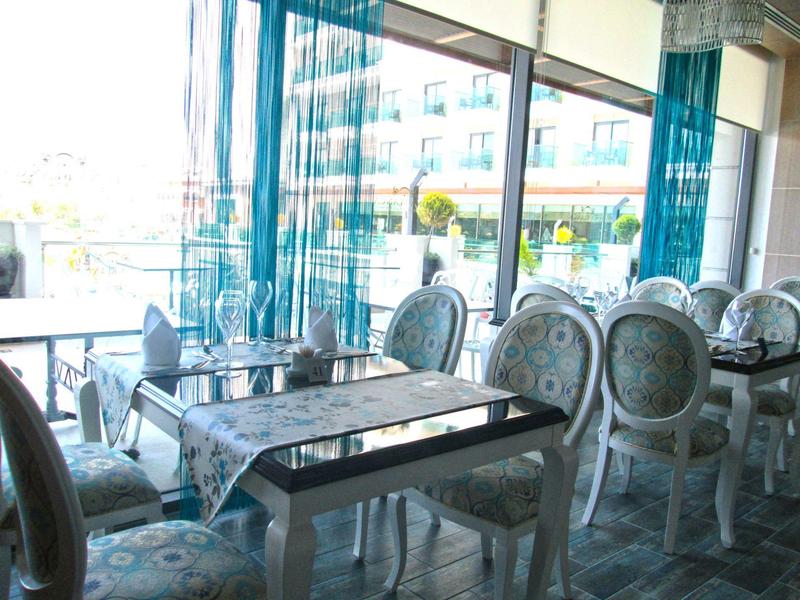 Área de comedor elegante en el hotel con sillas decorativas y grandes ventanas con vistas al exterior.