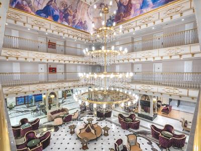 Salon élégant avec lustres, plafond peint artistiquement et coins salons confortables.