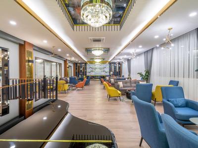 Salon d'hôtel moderne avec fauteuils colorés et piano élégant sous des lustres.