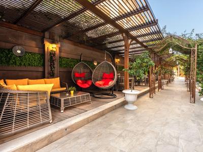 Espace extérieur confortable avec fauteuils suspendus et auvent en bois dans un hôtel.