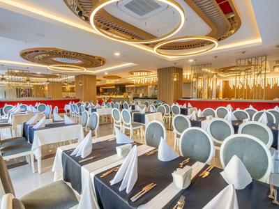 Salle à manger élégante avec tables dressées et lustres modernes.