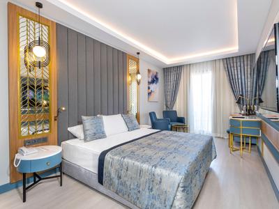 Chambre d'hôtel moderne avec grand lit, coin salon et espace bureau.