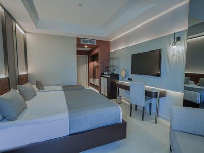 Chambre d'hôtel moderne avec lit double, bureau, télévision et éclairage chaleureux.