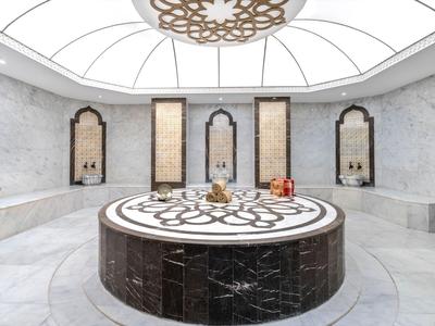 Jasna, okrągła marmurowa fontanna w luksusowym, misternie zaprojektowanym hammam z sklepionym sufitem.