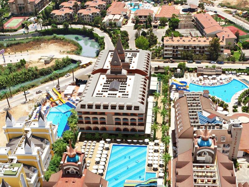 Aerial view of a large holiday resort with multiple swimming pools, buildings, and greenery.