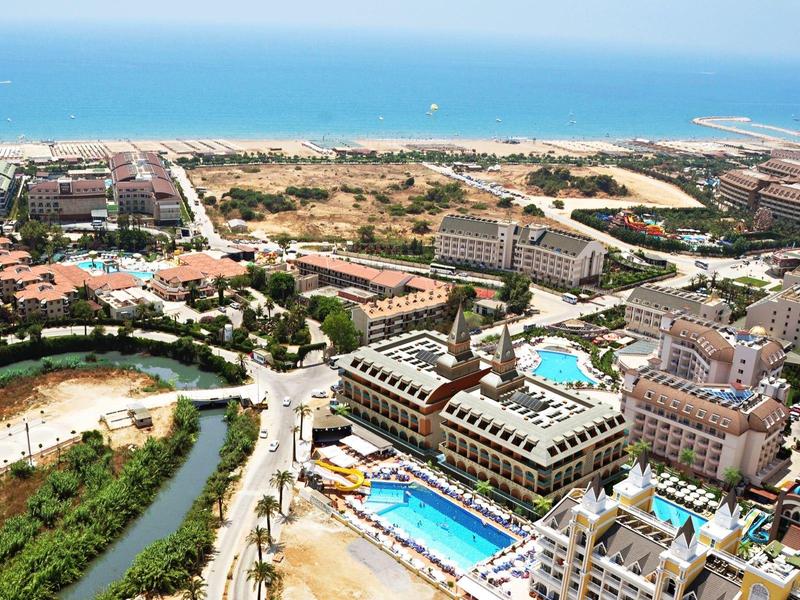 Aerial view of a resort with multiple pools, buildings, and sea in the background.
