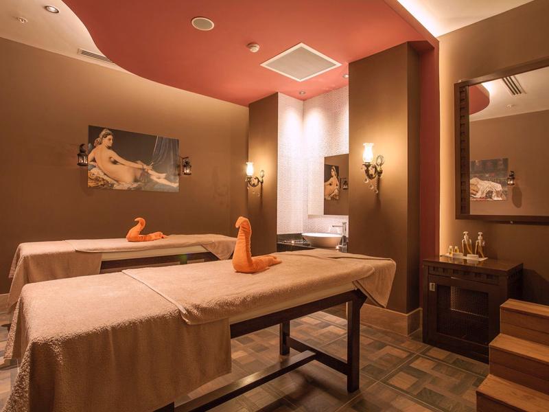 Cozy wellness room with two massage tables and warm lighting.