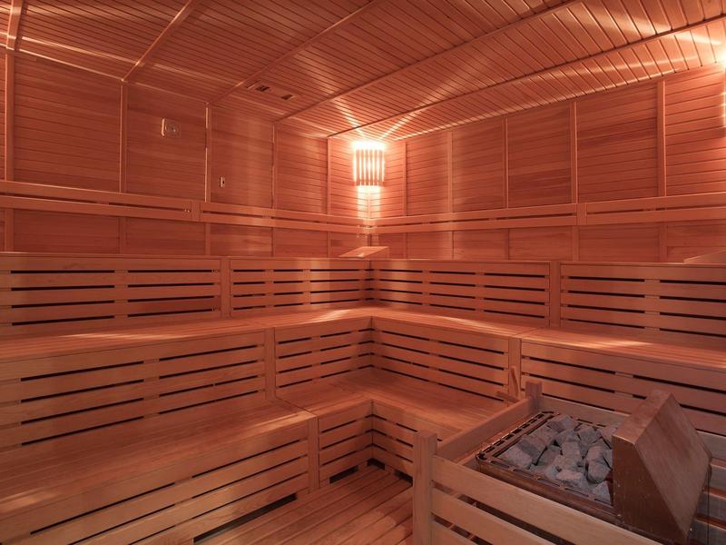 Brightly lit sauna with wooden paneling and a sauna heater in the corner.