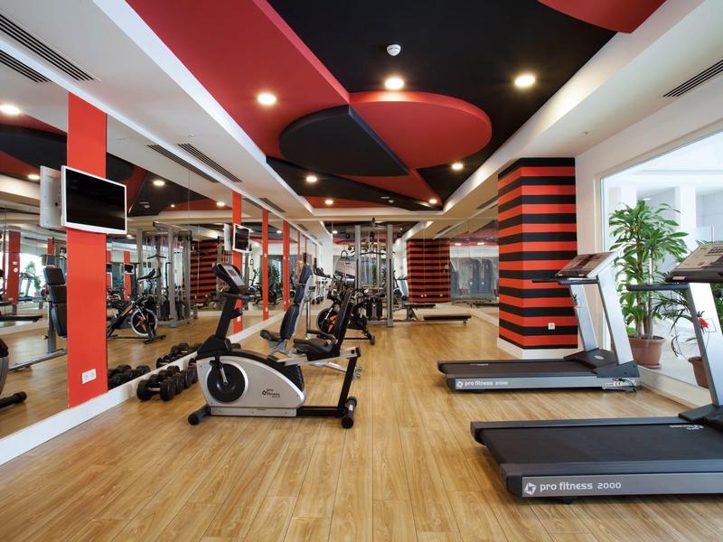Modern gym with treadmills, exercise bikes, and mirrors in a hotel.