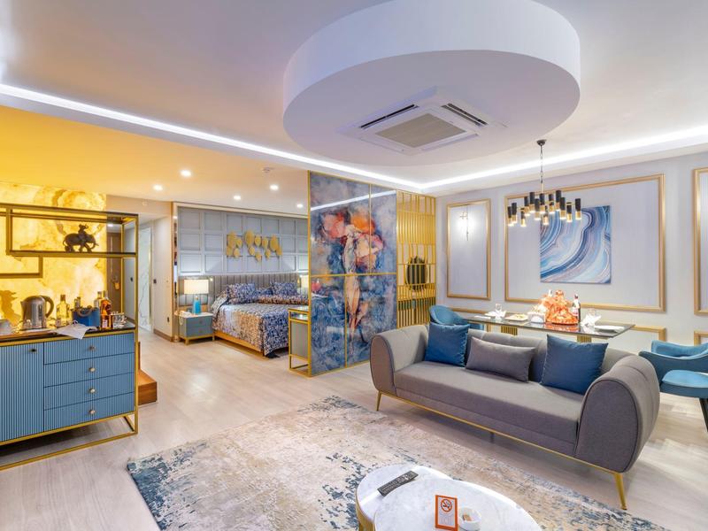 Modern hotel lounge area with armchairs, sofas, carpet, and decorative lighting.