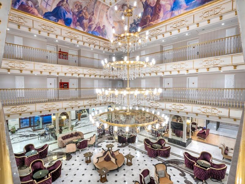 Elegant hotel lobby area with chandelier and artistically painted ceiling mural