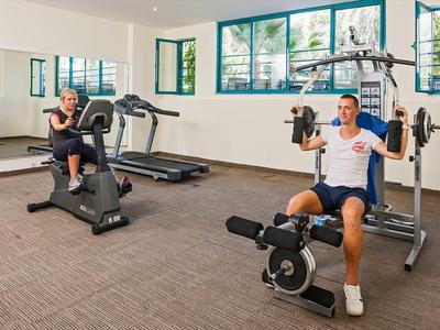 Zwei Männer trainieren in einem gut beleuchteten Fitnessraum mit Geräten und großen Fenstern.