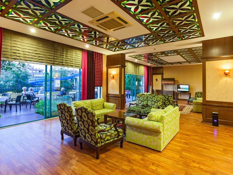 Przytulna przestrzeń wypoczynkowa hotelu z jasną drewnianą podłogą i dostępem do tarasu.