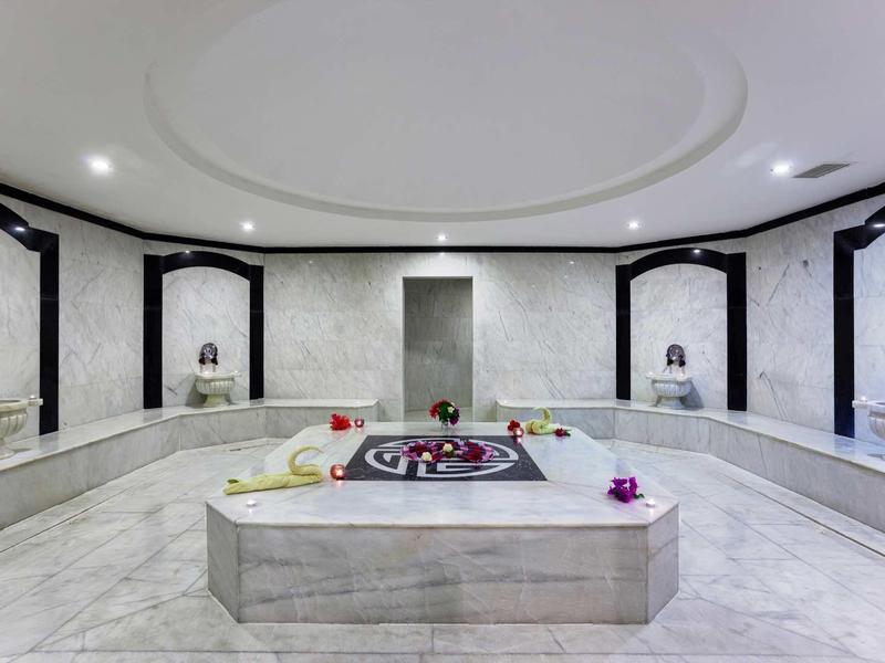 Nowoczesny turecki hammam z centralną fontanną i otaczającymi marmurowymi ławkami.