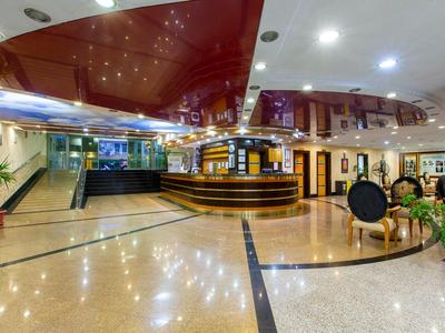 Große, moderne Hotellobby mit glänzendem Fußboden, Barbereich und stilvollen Sitzgelegenheiten.