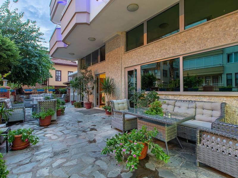 Przytulny taras na zewnątrz z roślinami i miejscami do siedzenia przed budynkiem hotelu