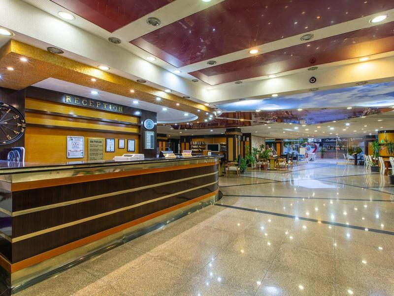 Nowoczesna lobby hotelowa z recepcją, jasnym oświetleniem i błyszczącą marmurową podłogą.