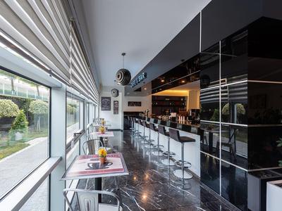 Moderne hotelbar met zwarte barkrukken, glanzende vloer en groot raam.