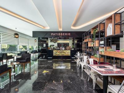 Modern café met glanzende marmeren vloer, zwarte zitplaatsen en patisseriebalie