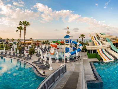 Waterpark met meerdere glijbanen, zwembad en ligstoelen bij zonsondergang.