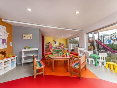 Kleurrijke kinderspeelruimte met tafels, stoelen en speelgoed in een hotel.