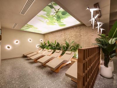 Moderne ontspanningsruimte met ligstoelen, planten en verlicht plafond in een hotel.