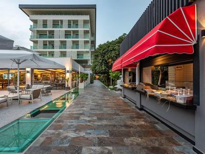 Ruim buitenterrein van een hotel met zitplaatsen, glazen vloer en rood zonnescherm.