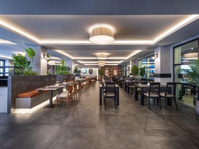 Intérieur moderne de restaurant d'hôtel avec tables, chaises et éclairage de plafond lumineux.
