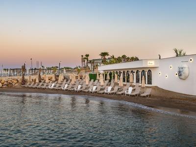 Hôtel de plage avec chaises longues au bord de la mer au coucher du soleil.