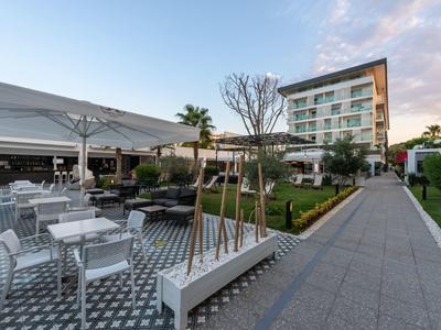 Moderne hotel tuin met zitgedeeltes, groene gazons en een meerlaagse gebouw op de achtergrond.