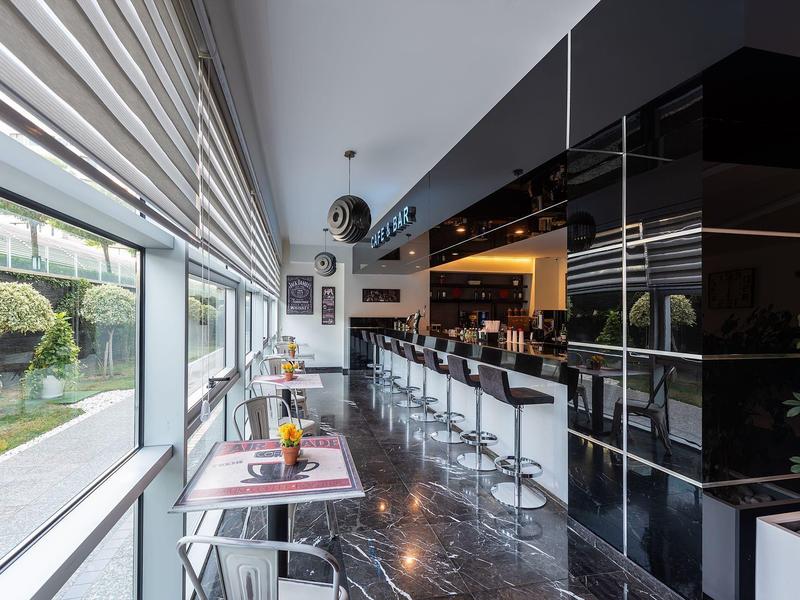 Moderne hotelbar met zwarte barkrukken, glanzende vloer en groot raam.