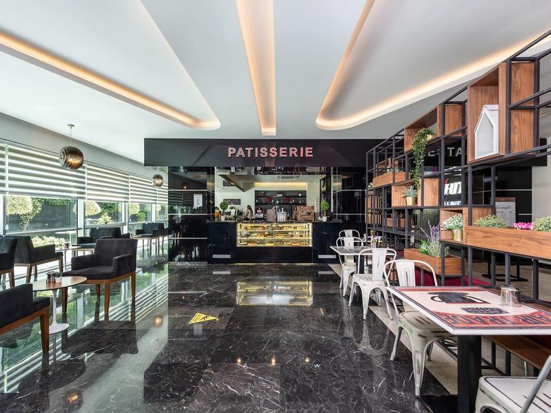 Modern café met glanzende marmeren vloer, zwarte zitplaatsen en patisseriebalie