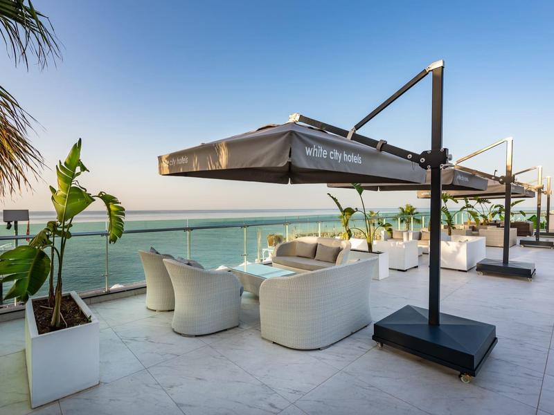 Moderne terras met zitmeubilair en zeezicht onder heldere hemel.