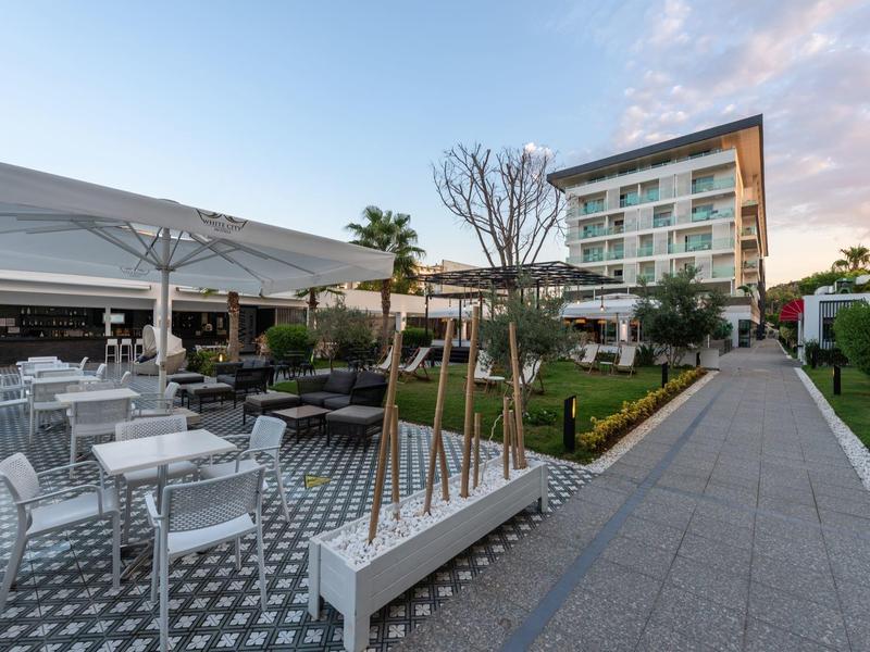 Moderne hotel tuin met zitgedeeltes, groene gazons en een meerlaagse gebouw op de achtergrond.