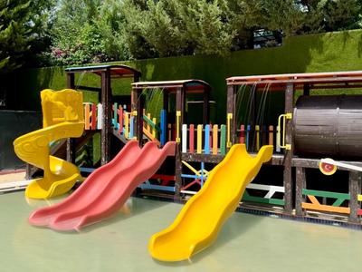 Barevné dětské hřiště s klouzačkami a prolézačkami pod modrou oblohou.