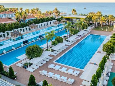 Moderní hotelová bazénová oblast se dvěma velkými bazény, lehátky a zahradami s výhledem na moře.