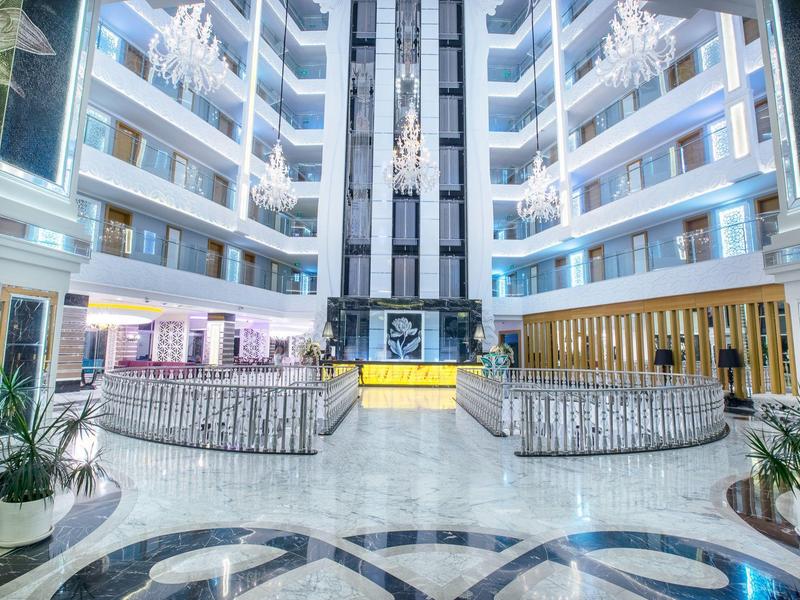 Světlá, moderní hotelová lobby s lesklou mramorovou podlahou a několika patry s balkóny.